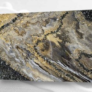 A mixed-media abstract art piece featuring a resin-coated surface with swirling black, gold, and silver patterns, textured with black fire glass, gold gems, and gold foil flakes.