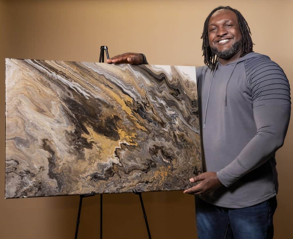 image of Artist James Sanders with an artpiece against a brown backround