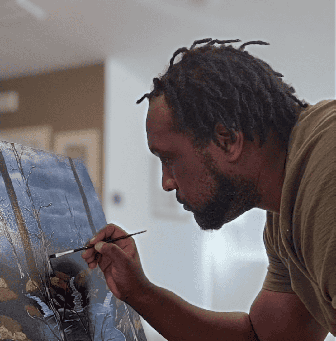 Profile view of artist James Sanders painting on an art canvas.